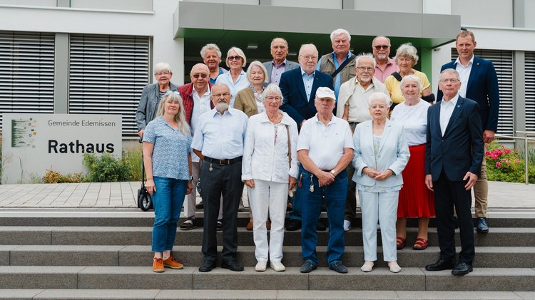 Eine gemischte Gruppe älterer Menschen auf den Stufen des Rathauses von Edemissen.