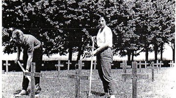 Historisches Foto. Zwei junge Erwachsene arbneiten auf einer Kriegsgräberstätte mit einfachen Holzkreuzen. Die junge Frau blickt in die Kamera.