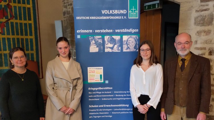 Von links nach rechts: eine Frau, zwei Mädchen und ein Mann. Dazwischen ein blaues Rollup des Volksbundes