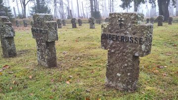Auf einer Rasenfläche steinerne Grabkreuze mit der Inschrift „unbek. Russe“.