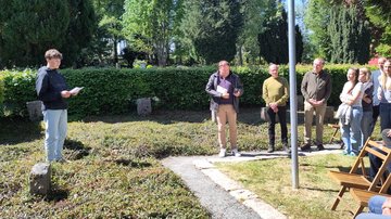 Links ein Schüler. Er liest von einem Blatt ab. Rechts Zuhörer.