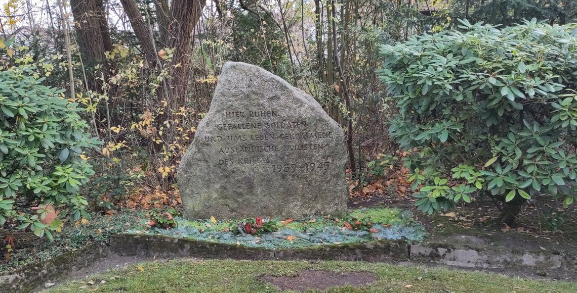 Ein Gedenkstein mit der Inschrift: „Hier ruhen gefallene Soldaten und uns Leben gekommene ausländische Zivilisten des Krieges 1939–1945.“ 